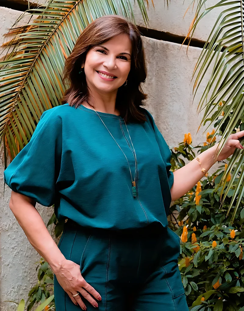 Dra. Mônica Fernandes sorrindo entre folhagens
